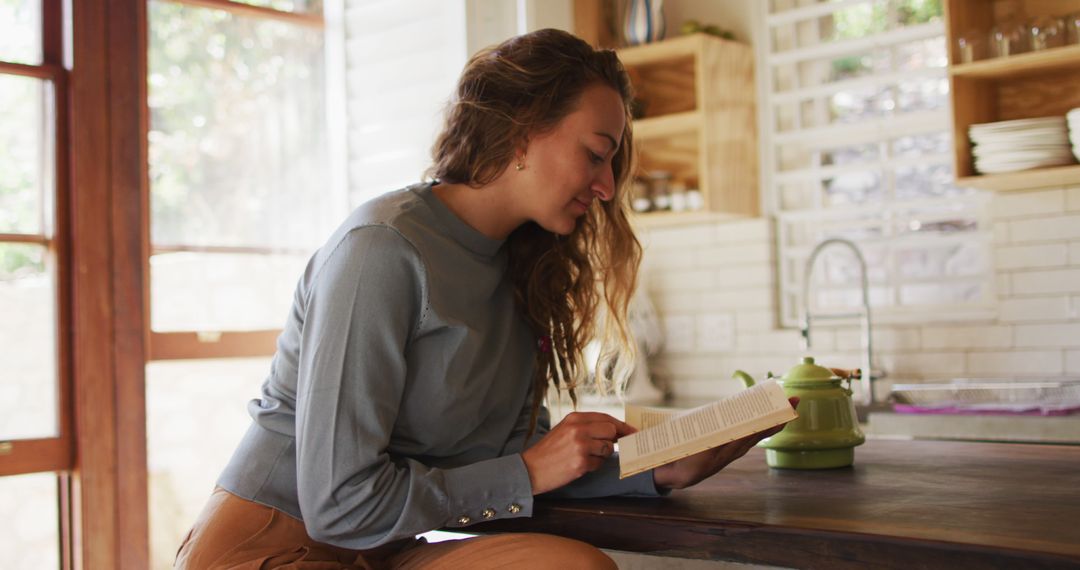 Young Woman Reading Book in Cozy Kitchen Interior - Free Images, Stock Photos and Pictures on Pikwizard.com