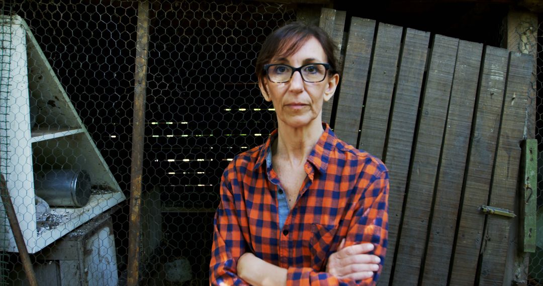 Serious woman standing with arms crossed in front of rustic wooden backdrop - Free Images, Stock Photos and Pictures on Pikwizard.com