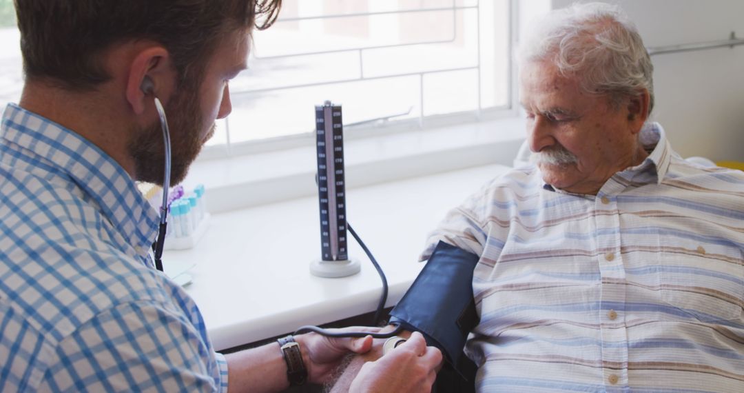 Doctor checking blood pressure of elderly male patient at clinic