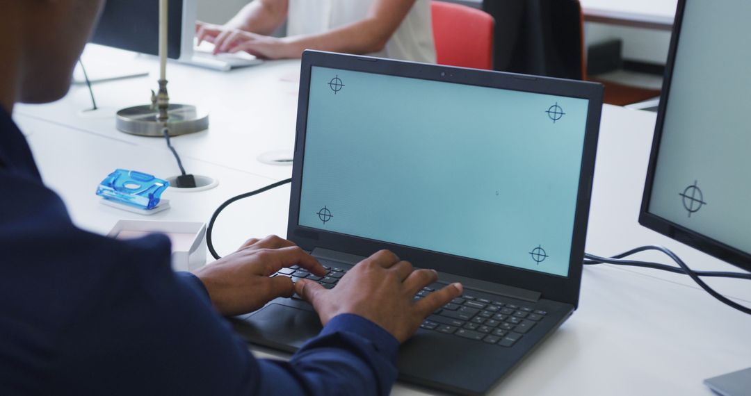 Hands Typing on Laptop in Modern Office with Dual Monitors