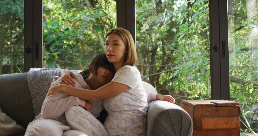 Mother Comforting Child on Couch Near Large Windows - Free Images, Stock Photos and Pictures on Pikwizard.com