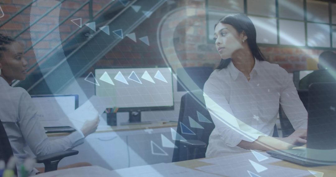 Collaborating colleagues reviewing laptop with digital HUD overlay in open-plan office