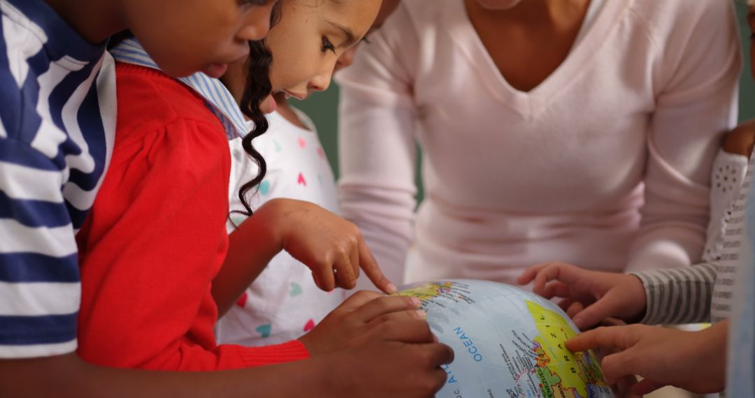Children and Teacher Exploring World on Globe in Classroom