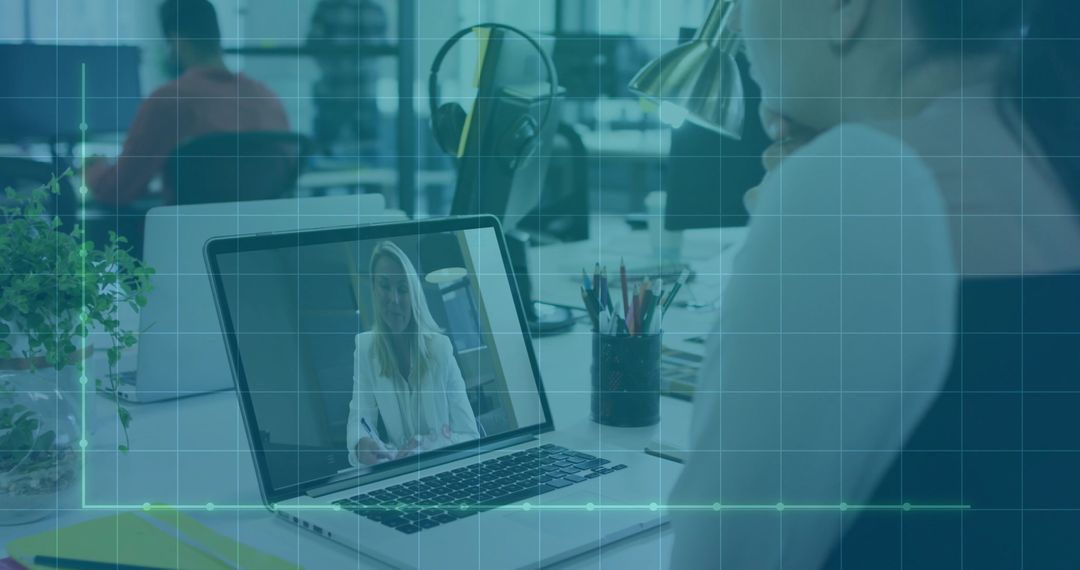 Remote team collaborating on video call in open-plan office, laptop showing consultant with headset
