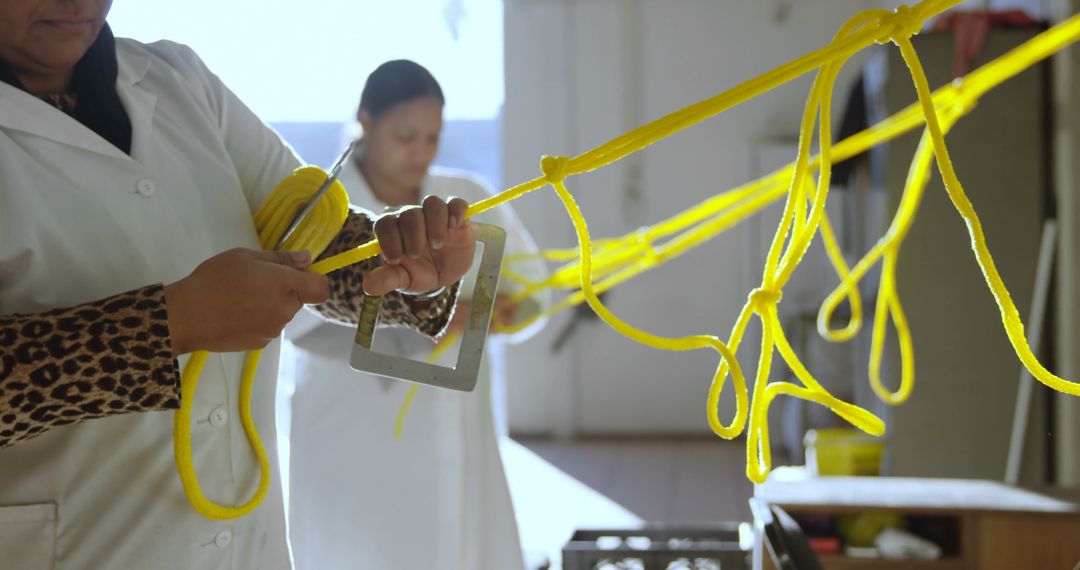 Women in Factory Using Bright Yellow Strings for Manual Work - Free Images, Stock Photos and Pictures on Pikwizard.com