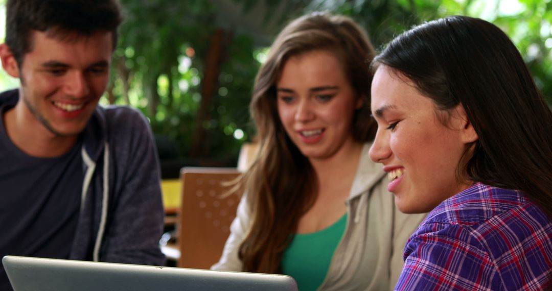 Friends Smiling While Studying on Laptop Outdoors - Free Images, Stock Photos and Pictures on Pikwizard.com