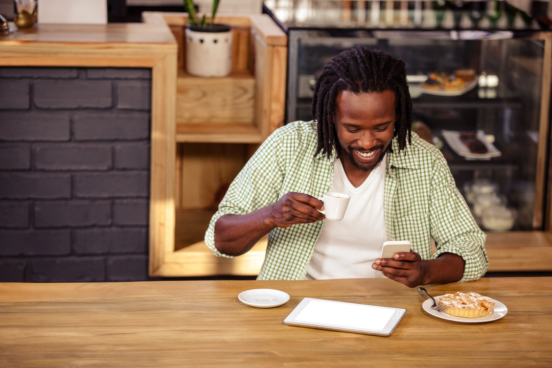 Smiling Man With Tablet and Coffee in Cozy Café Focused on Phone - Download Free Stock Images Pikwizard.com