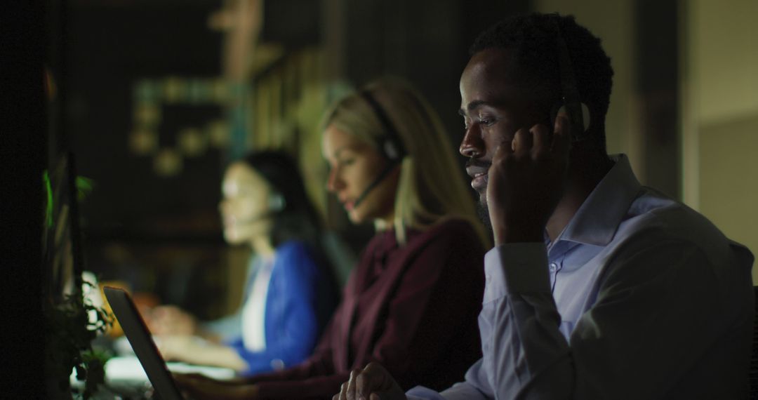 Image of smiling african american businessman and colleagues using headsets at night in office - Free Images, Stock Photos and Pictures on Pikwizard.com