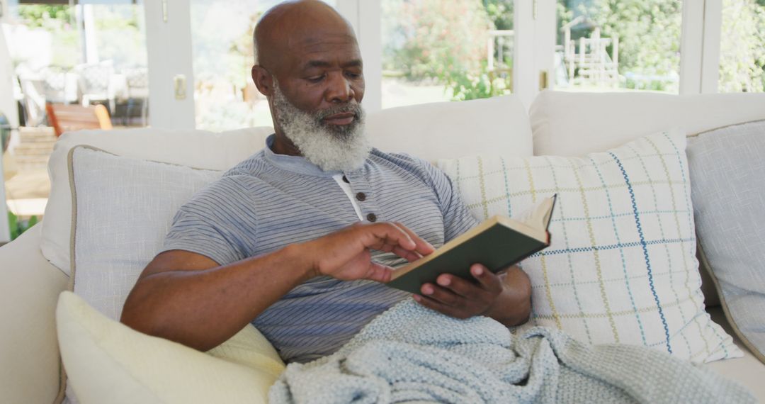 Elderly Man Relaxing on Couch at Home Reading Book - Free Images, Stock Photos and Pictures on Pikwizard.com