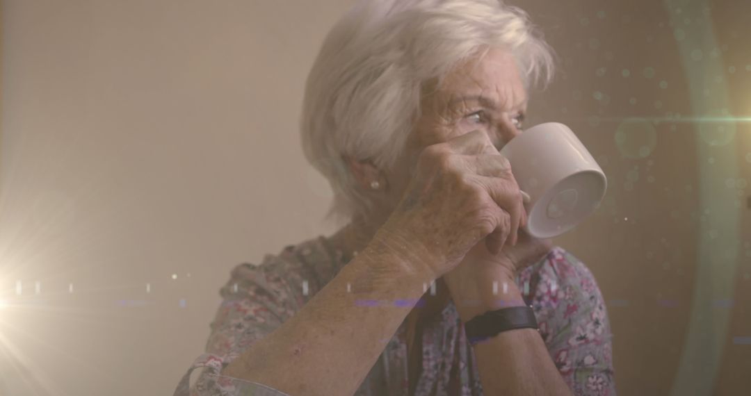 Image of glowing light over serious senior woman drinking tea - Free Images, Stock Photos and Pictures on Pikwizard.com