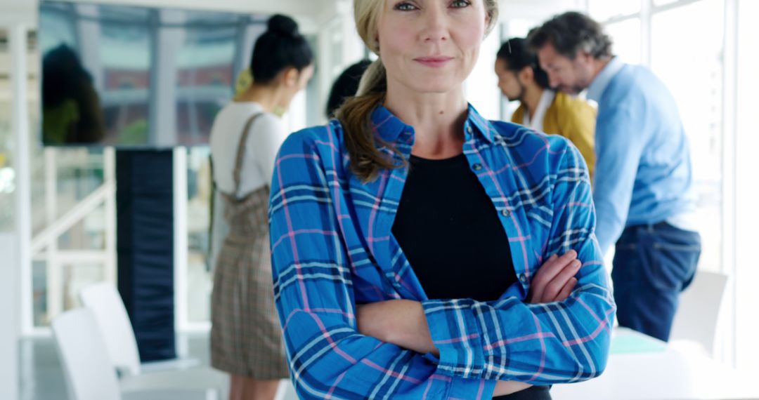 Confident Businesswoman in Modern Office with Team Collaborating in Background - Free Images, Stock Photos and Pictures on Pikwizard.com