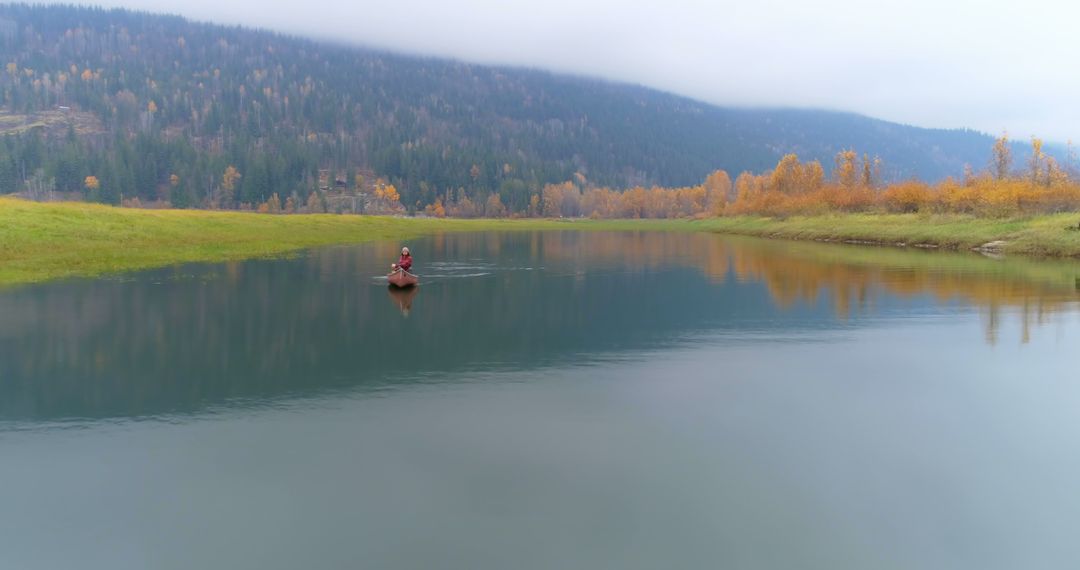 Lone Kayaker Paddling on Serene Lake with Autumn Forest and Snowy Mountains - Free Images, Stock Photos and Pictures on Pikwizard.com