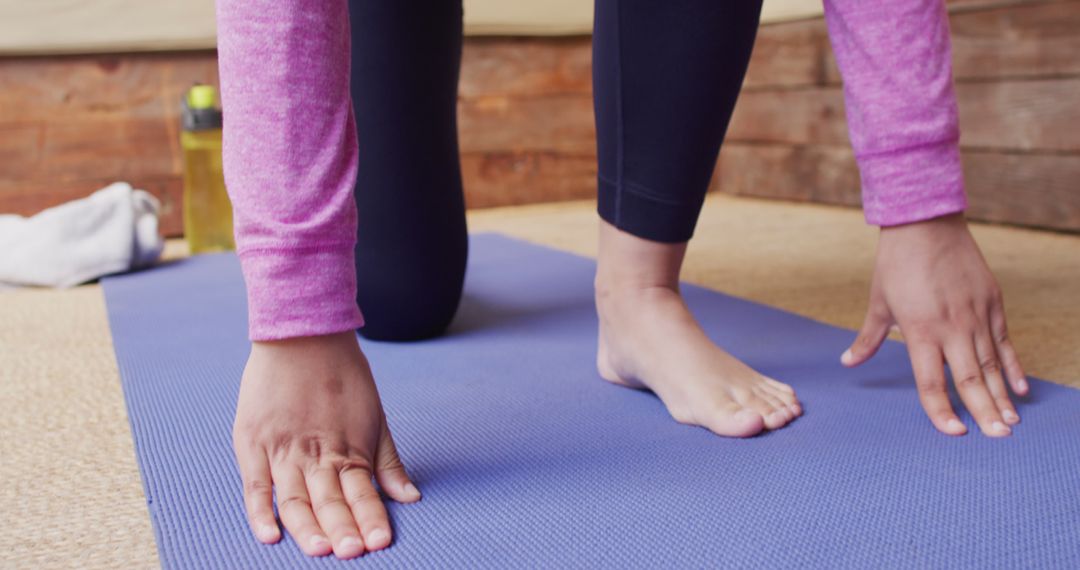 Image of relaxed biracial woman in hijab stretching leg in yoga pose kneeling on mat in living room - Free Images, Stock Photos and Pictures on Pikwizard.com