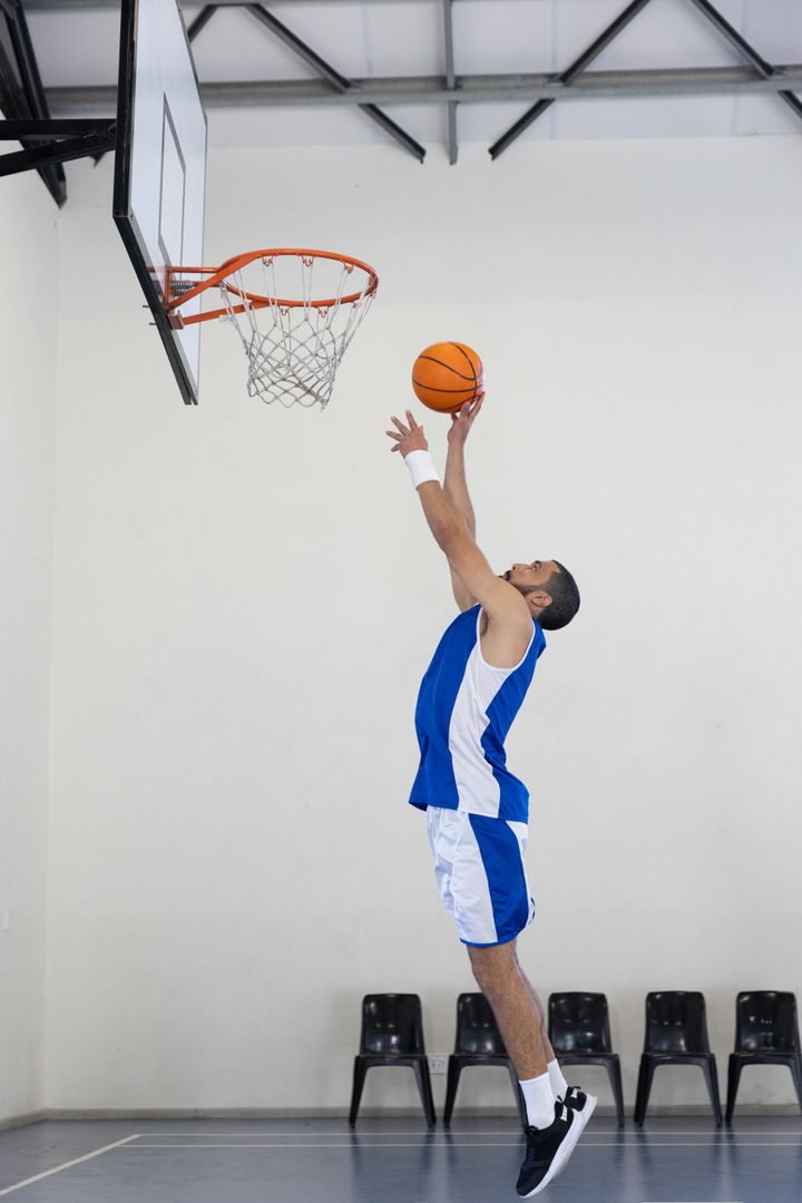 Basketball Player Leaping with Energy Towards Hoop in Gym