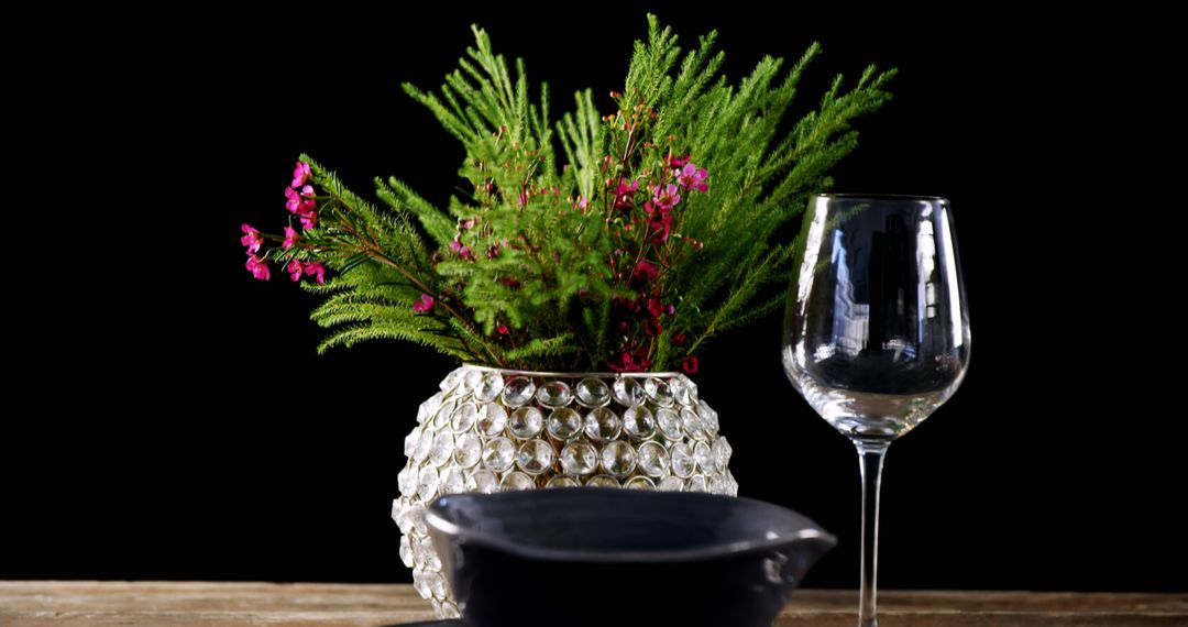 A green plant with pink blooms in a glass vase creates a striking contrast on a wooden surface. - Free Images, Stock Photos and Pictures on Pikwizard.com