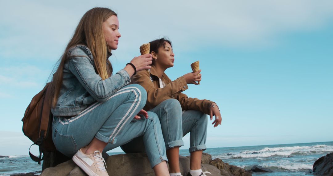 Young Women Enjoying Ice Cream by the Sea on a Sunny Day - Free Images, Stock Photos and Pictures on Pikwizard.com