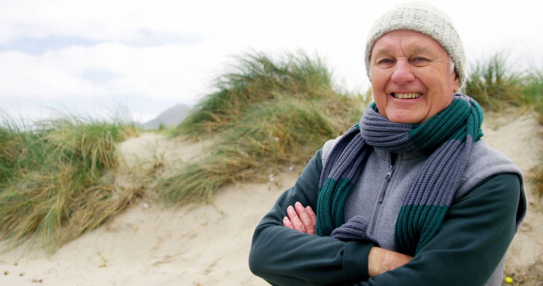 Smiling senior man in winter clothes enjoying beach walk in winter - Free Images, Stock Photos and Pictures on Pikwizard.com