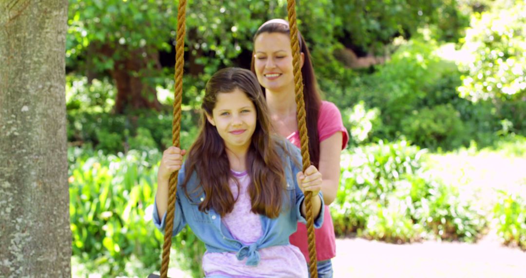 Mother pushing her daughter on a swing in the playground on a sunny day - Free Images, Stock Photos and Pictures on Pikwizard.com