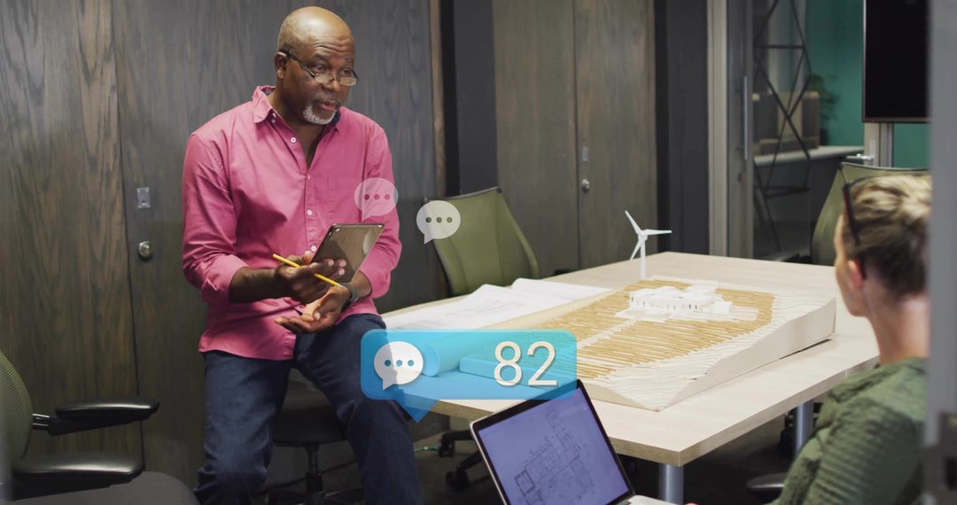 Senior Architect Discussing Project Model in Modern Office Environment