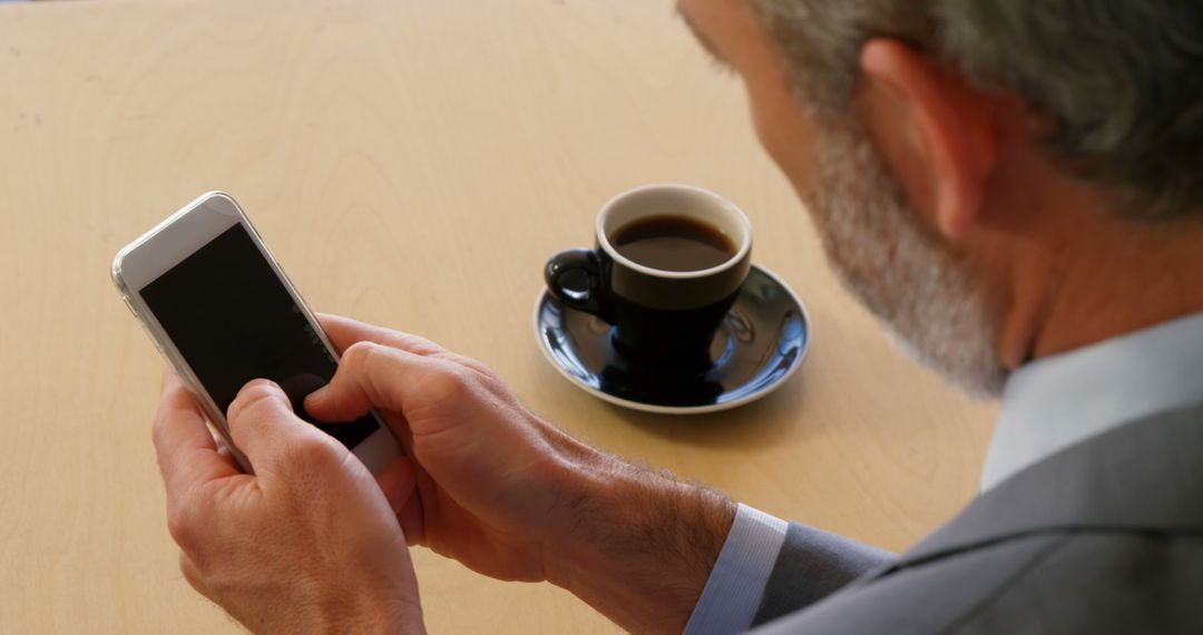 Businessman Using Smartphone with Coffee on Desk - Free Images, Stock Photos and Pictures on Pikwizard.com