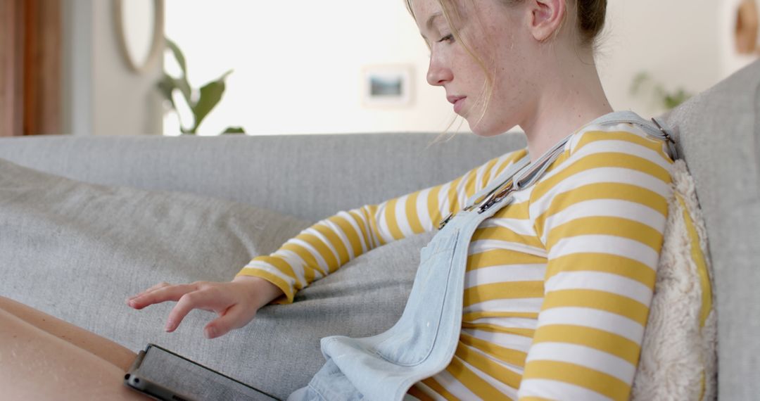 Teenage Girl Relaxing on Couch Using Tablet - Free Images, Stock Photos and Pictures on Pikwizard.com