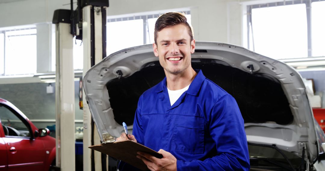 Happy Auto Mechanic Holding Clipboard in Car Workshop - Free Images, Stock Photos and Pictures on Pikwizard.com