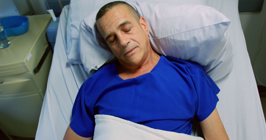 Hospital patient resting in bed wearing blue gown - Free Images, Stock Photos and Pictures on Pikwizard.com