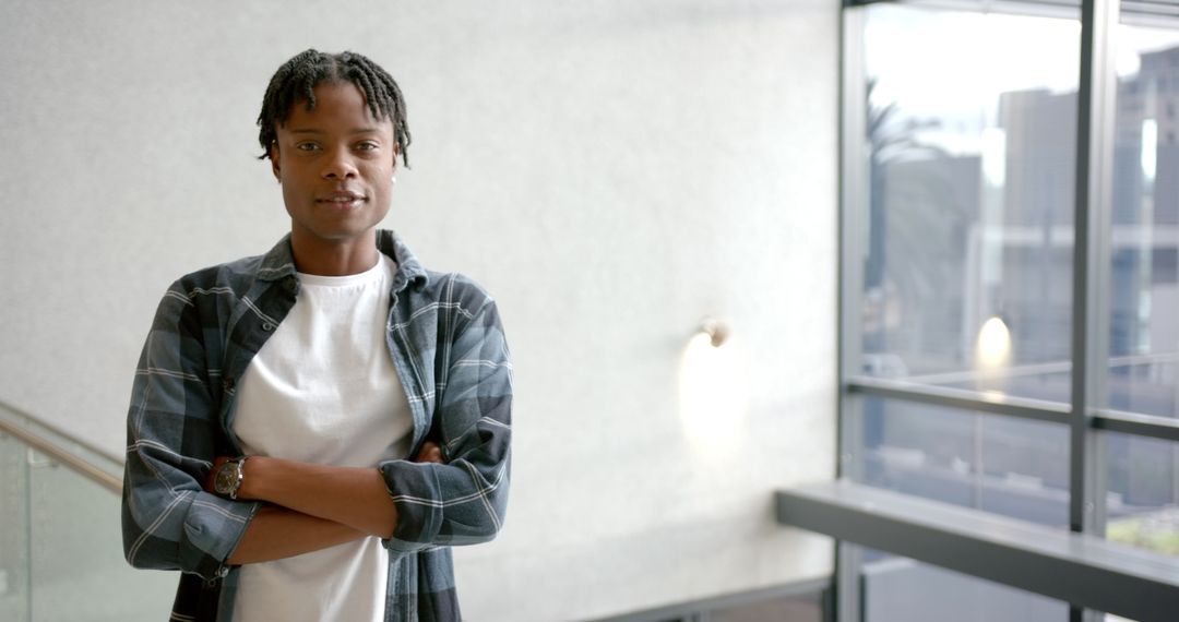 Confident Young Man in Modern Office Environment with Arms Crossed