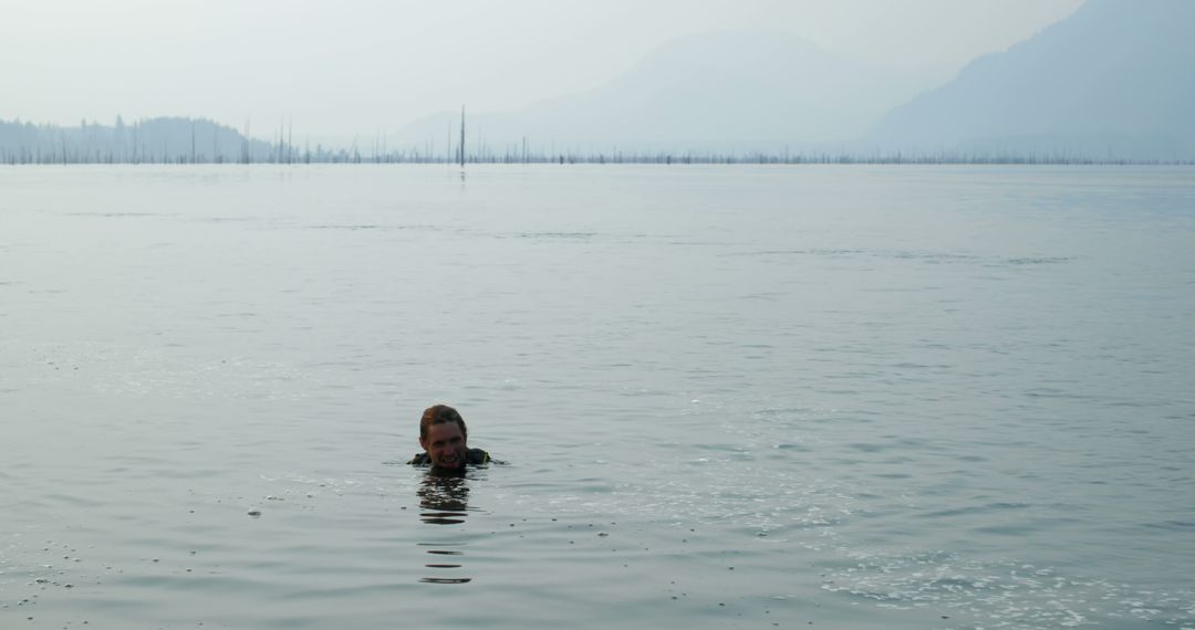 Man Swimming in Serene Mountain Lake at Dusk - Free Images, Stock Photos and Pictures on Pikwizard.com