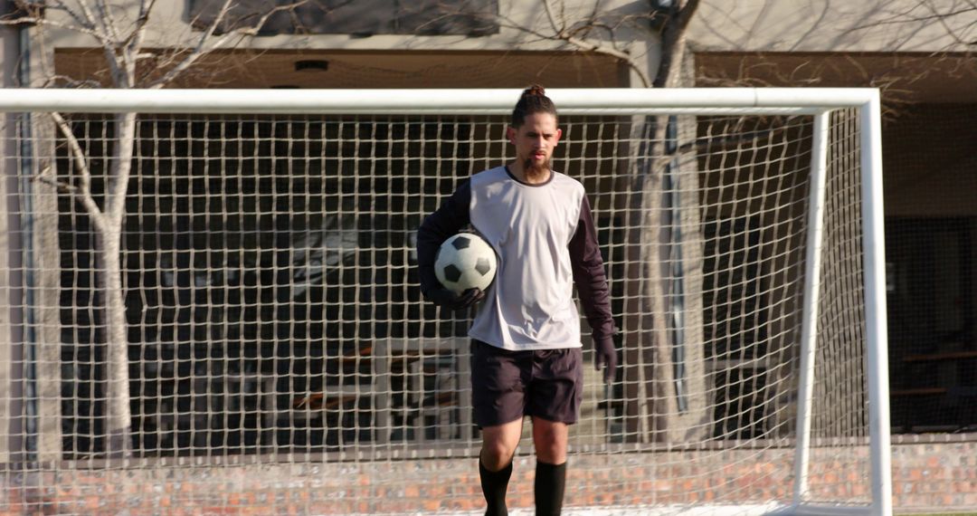 Soccer Player Walking Near Goalpost on Sunny Day