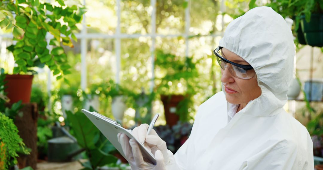 Scientist Analyzing Plants in Greenhouse with Protective Suit - Free Images, Stock Photos and Pictures on Pikwizard.com