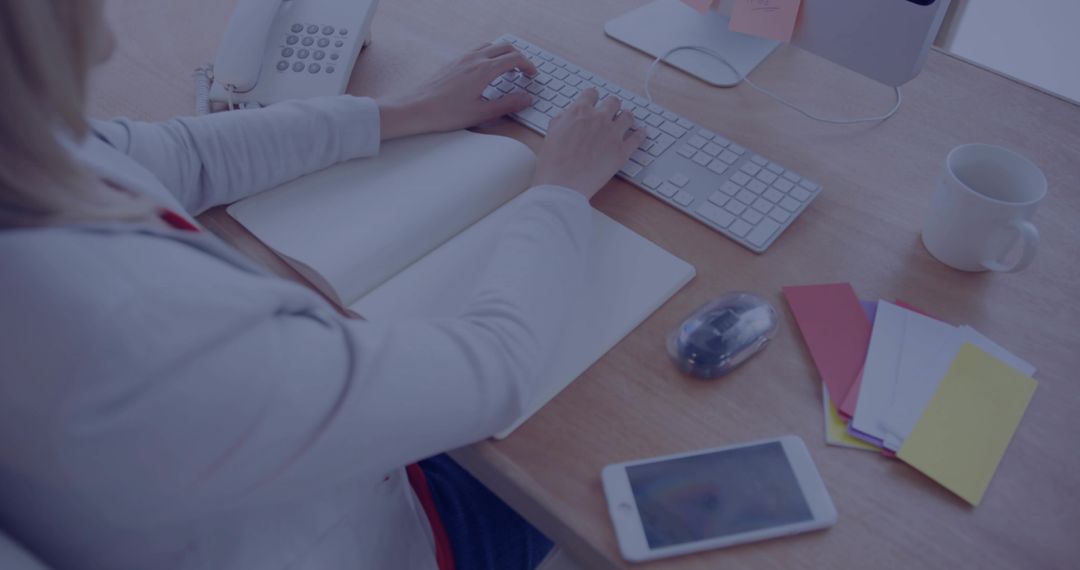 Professional Woman Typing at Modern Workspace with Notebook and Smartphone