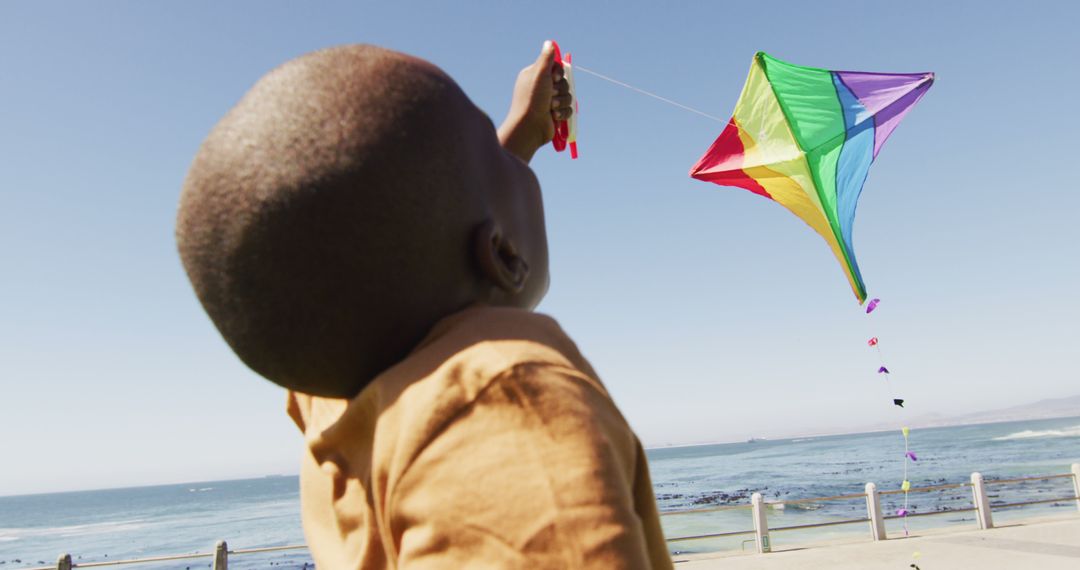 Child Flying Colorful Kite Near Ocean on Sunny Day - Free Images, Stock Photos and Pictures on Pikwizard.com