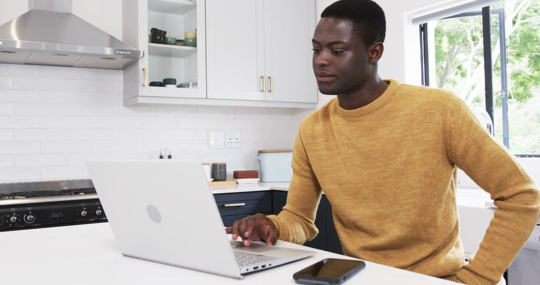 Professional Man Working on Laptop in Bright Home Kitchen