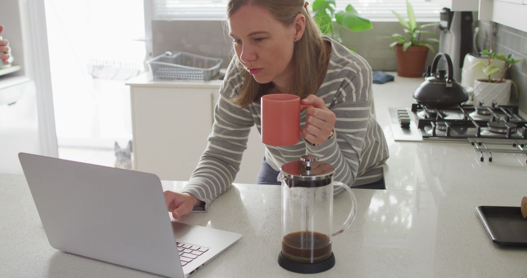 Woman Having Coffee and Working on Laptop in Kitchen - Free Images, Stock Photos and Pictures on Pikwizard.com