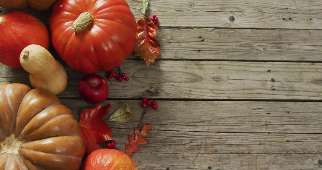 Displaying autumn harvest flatlay with pumpkins, gourds, apple and berries on rustic wood
