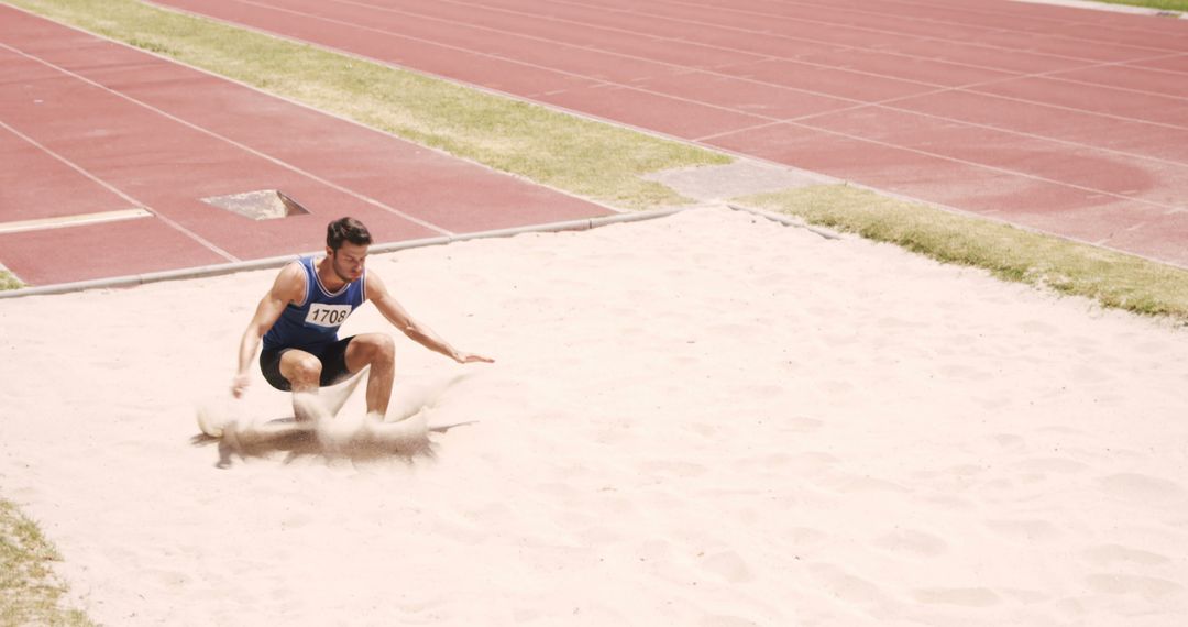 Athlete Landing in Long Jump Sand Pit During Competition - Free Images, Stock Photos and Pictures on Pikwizard.com