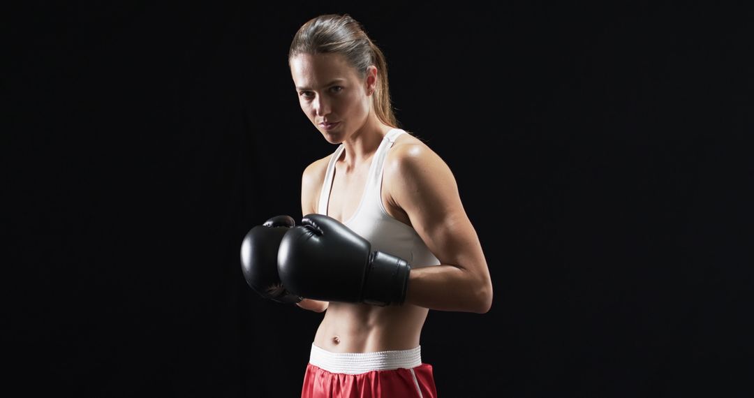 Female Boxer Showing Strength in Studio Pose with Boxing Gloves