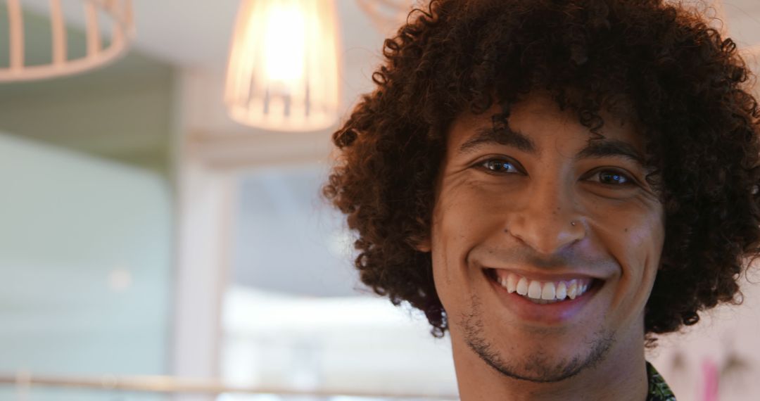 Smiling Young Man with Curly Hair in Bright Interior - Free Images, Stock Photos and Pictures on Pikwizard.com