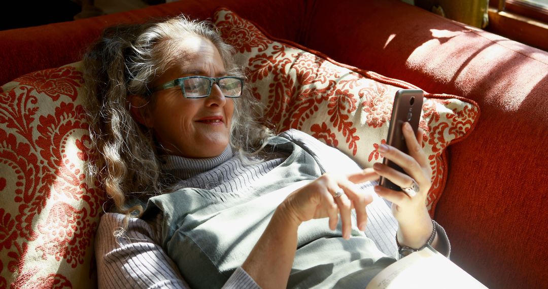 Elderly Woman Relaxing on Sofa Using Smartphone - Free Images, Stock Photos and Pictures on Pikwizard.com