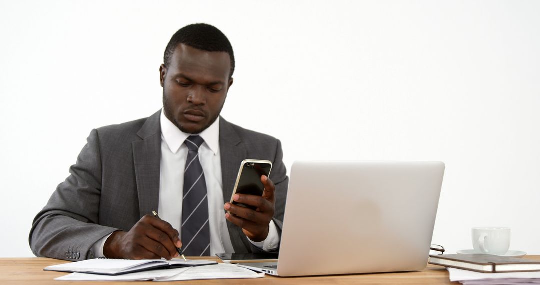 African American Businessman Working at Desk Using Smartphone and Laptop - Free Images, Stock Photos and Pictures on Pikwizard.com