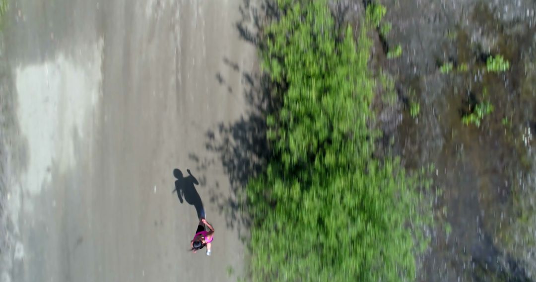 Aerial View of Person Jogging Alongside Lush Greenery on Empty Road - Free Images, Stock Photos and Pictures on Pikwizard.com