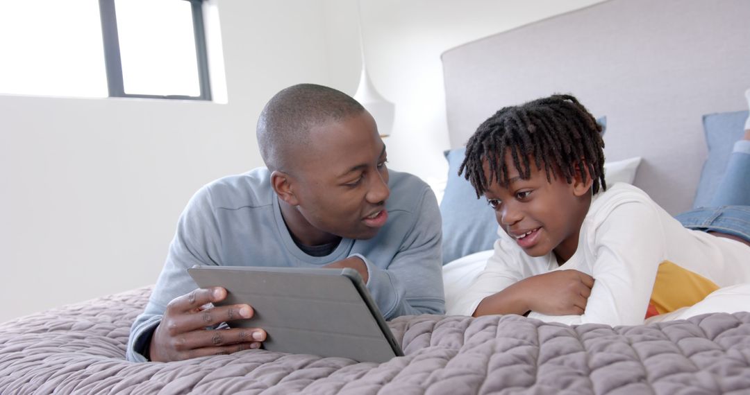 Father and Son Reading Digital Tablet on Bed - Free Images, Stock Photos and Pictures on Pikwizard.com