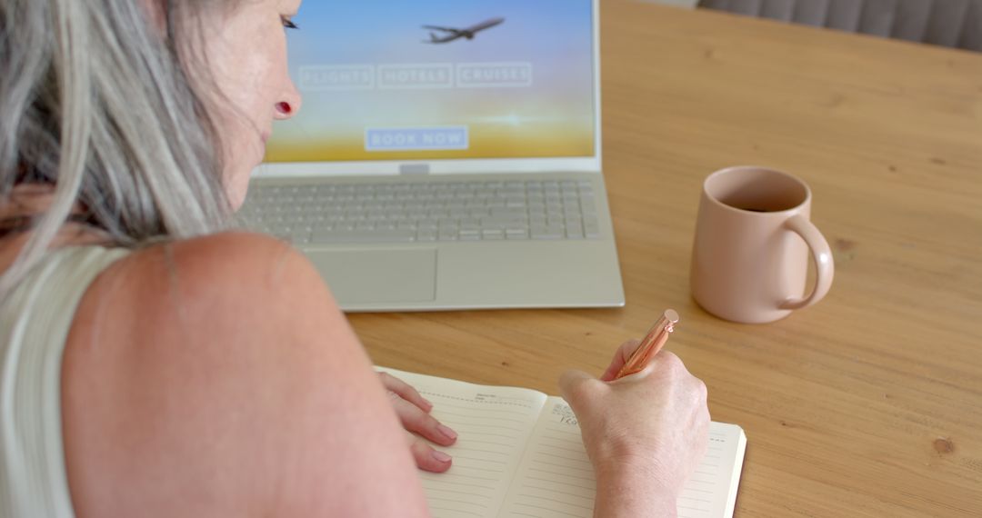 Mature Woman Planning Travel with Notebook and Laptop