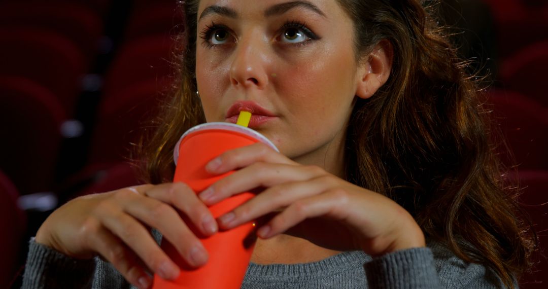 Woman enjoying beverage at movie theater - Free Images, Stock Photos and Pictures on Pikwizard.com