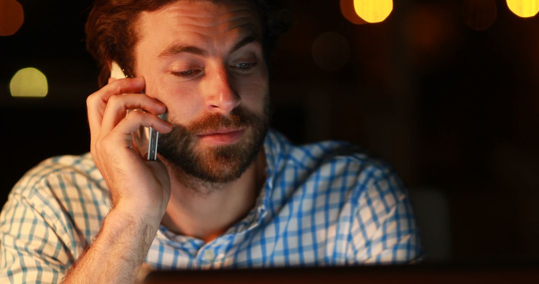 Man talking on phone while working late at night in office - Free Images, Stock Photos and Pictures on Pikwizard.com