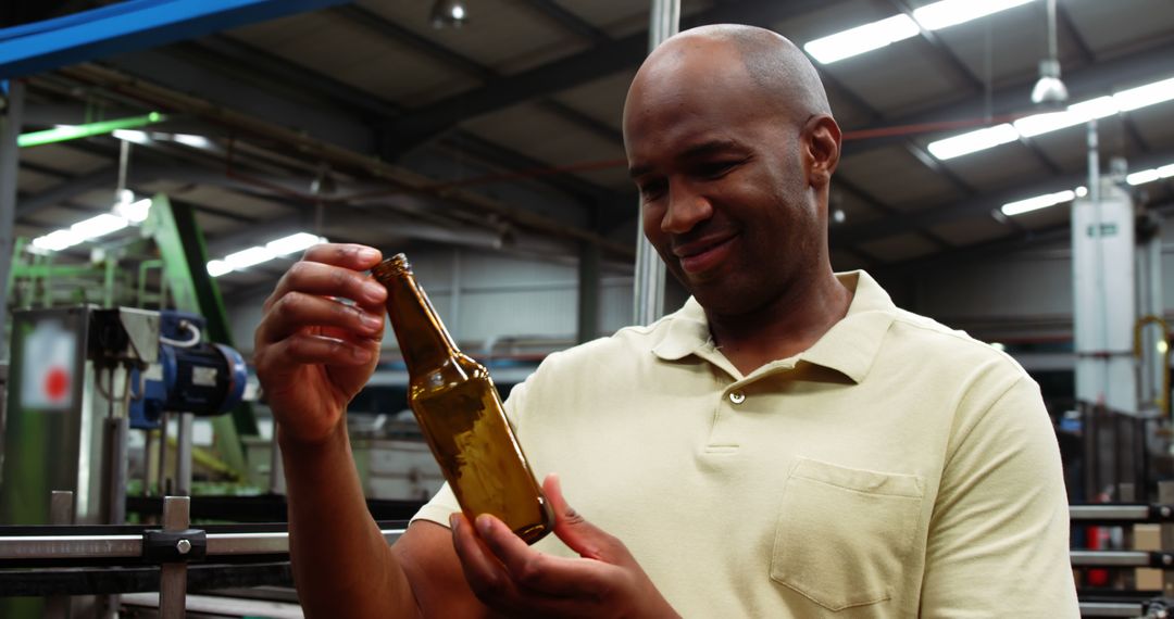 African American Man Holding Beer Bottle in Brewery Factory - Free Images, Stock Photos and Pictures on Pikwizard.com