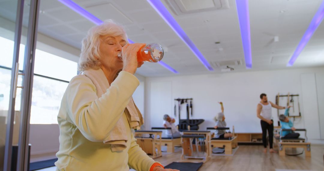 Senior Woman Refreshing after Pilates Session in Modern Fitness Studio - Free Images, Stock Photos and Pictures on Pikwizard.com