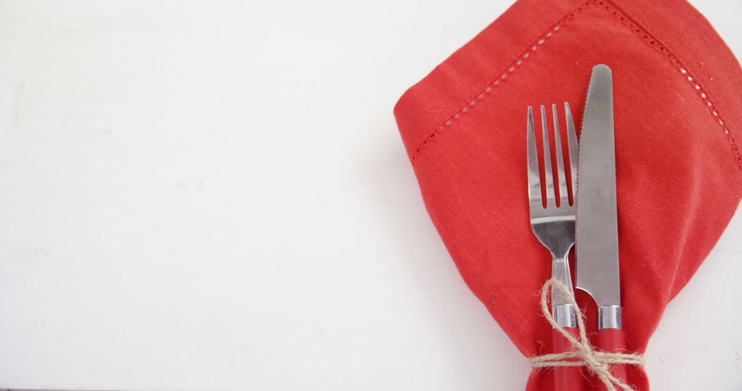 A fork and knife are neatly wrapped in a red napkin, with copy space - Free Images, Stock Photos and Pictures on Pikwizard.com