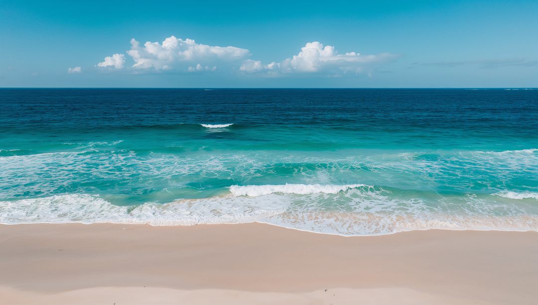 Turquoise Waves Rolling onto Pristine Sand under Blue Sky with Puffy Cumulus Clouds